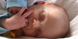rosto de recém-nascido de olhos fechados e dedos na boca ilustra artigo sobre a visão do prematuro